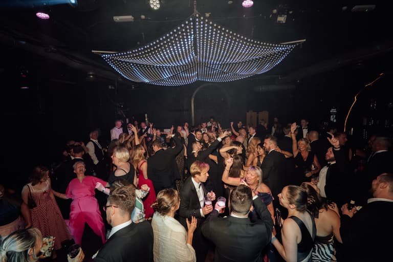 Guests dancing at an event beneath a light canopy